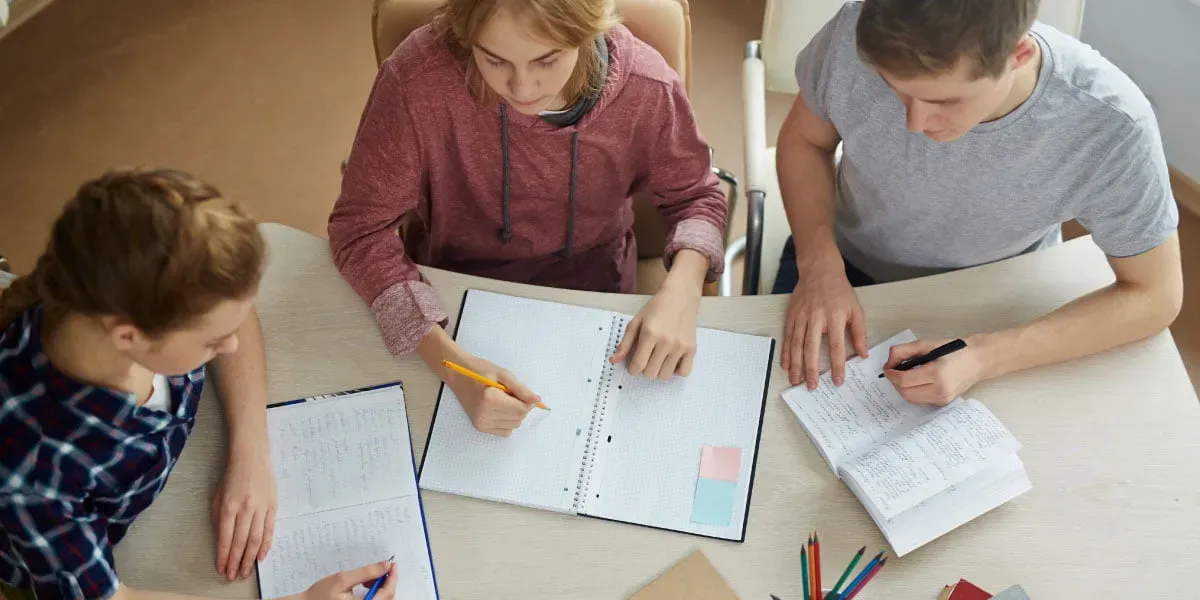 Three teenagers studying around a table