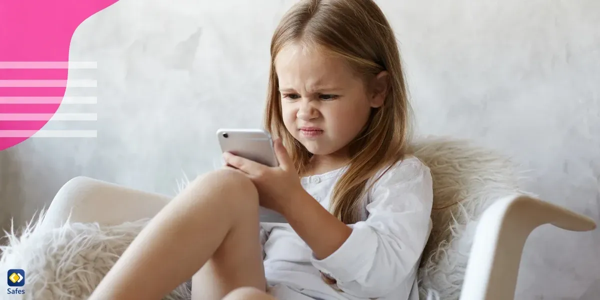 Irritated little girl looking at phone