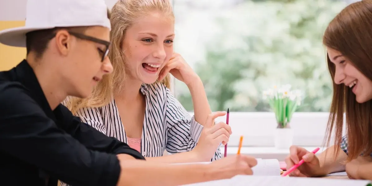 Three laughing students studying together