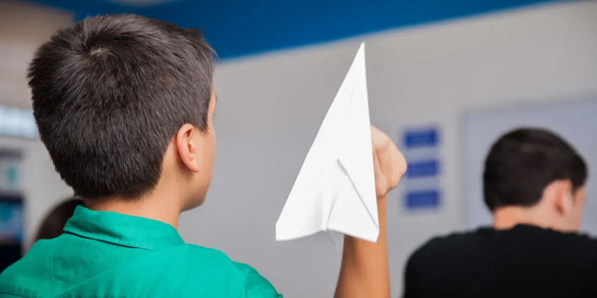 naughty high school student throwing a paper plane during class