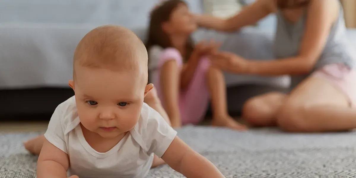 Mother and young girl talking while a baby is on the floor